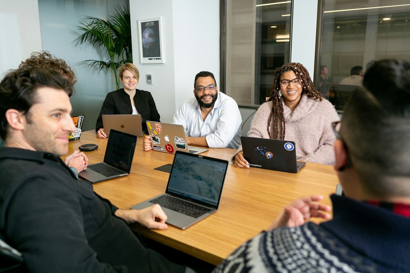 A small team smiling around a meeting table with laptops